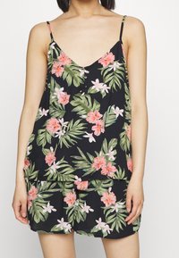 Černý top bez rukávů s květinovým vzorem s růžovými a bílými květy. Lehká tkanina s výstřihem do V a(detail) knoflíkovými detaily vpředu.