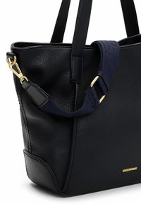 Czarna torba na ramię z ekologicznej skóry o fakturowanej powierzchni, wyposażona w podwójne uchwyty i regulowany granatowy pasek. Widoczne złote ozdoby.