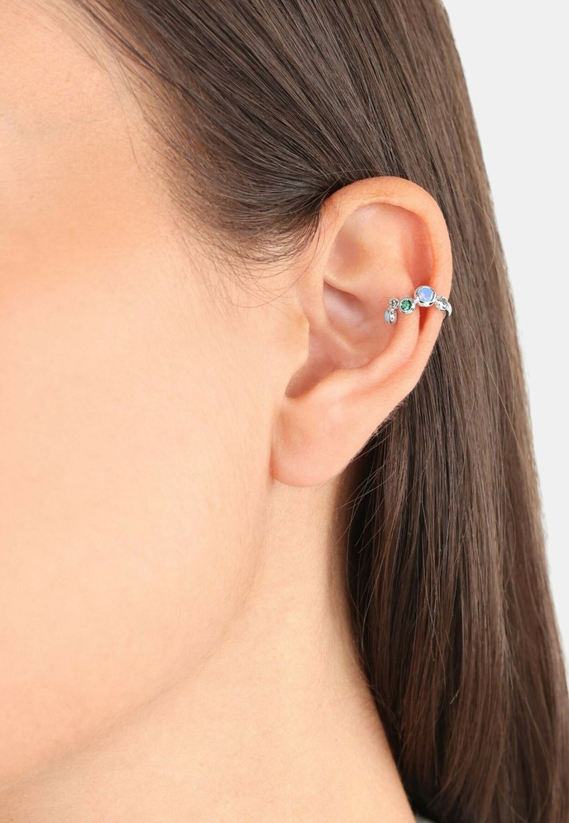 Pendiente en forma de cuff de plata que presenta piedras de colores variados. Diseño curvado que se envuelve alrededor de la parte exterior de la oreja. Textura suave con un acabado pulido.