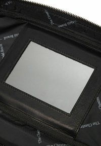 Borsa nera con zip e specchio rettangolare incorporato. Foderata con un tessuto liscio che presenta un motivo testuale ripetuto, design minimalista.
