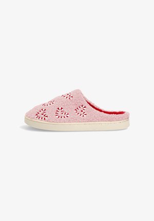 Zapatilla rosa y esponjosa con recortes en forma de corazón rojo, con un forro rojo que contrasta y una suela beige. Textura suave y diseño casual de espalda abierta.