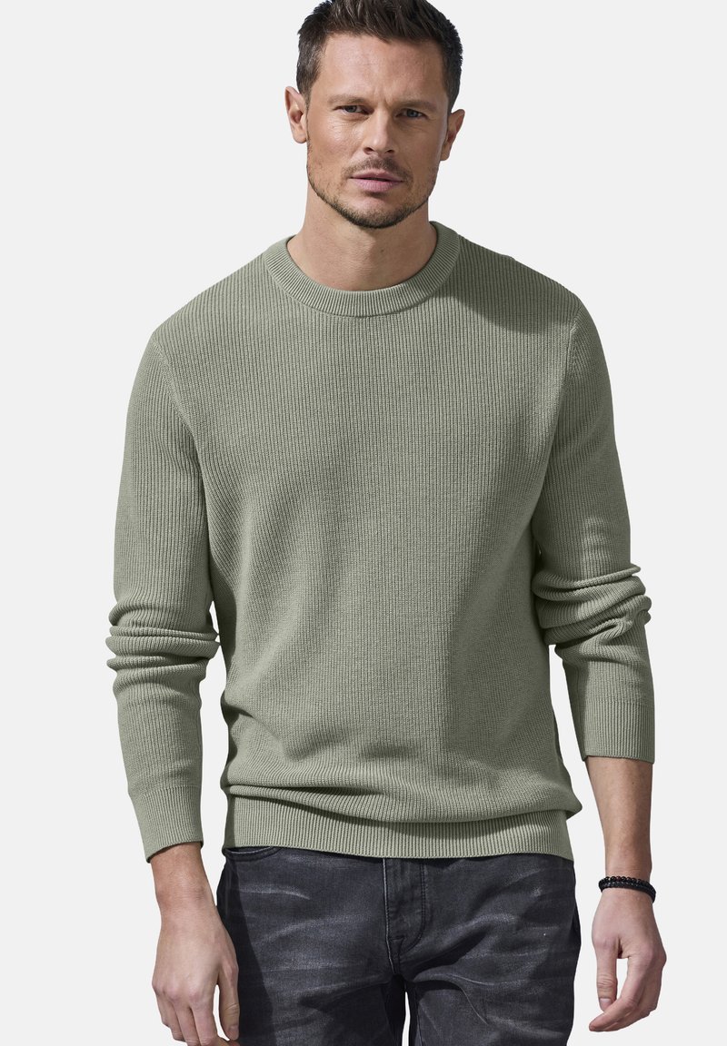 Strickpullover mit Rundhalsausschnitt in Hellgrün, mit gerippter Textur, langen Ärmeln und lockerer Passform, kombiniert mit dunklen Jeans.