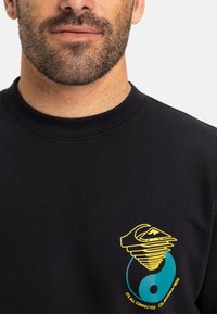 Black sweatshirt made of cotton, featuring a colorful graphic: yellow swirl design over a turquoise circle with a yin-yang symbol and text.