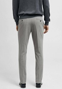Pantaloni grigi su misura con una texture liscia, taglio dritto, due tasche posteriori con bottoni neri e una piega sottile lungo la gamba.