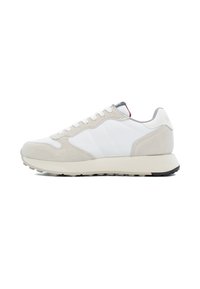 Zapatillas en un tono gris claro y blanco que combinan materiales de cuero y gamuza, con una suela texturizada y acentos de diseño minimalista.