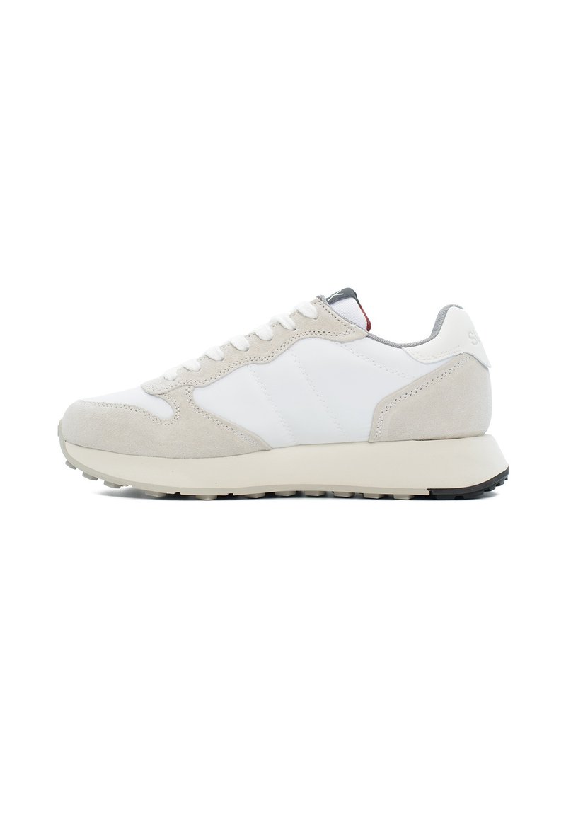 Zapatillas en un tono gris claro y blanco que combinan materiales de cuero y gamuza, con una suela texturizada y acentos de diseño minimalista.