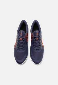 Chaussures de sport bleu foncé avec des accents orange et une texture en maille. Dotées d'un design à lacets et d'une semelle rembourrée pour plus de confort.