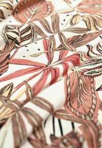 Tkanina z kwiatowym wzorem, na którym znajdują się duże liście w odcieniach różu i brązu na kremowym tle, z czarnymi kropkami i obrysami.