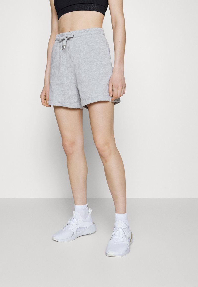 Shorts de sport gris avec une ceinture élastique et un cordon de serrage. Présentent une texture douce et une coupe droite, associés à des baskets blanches.