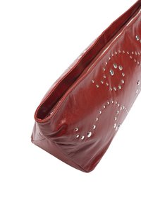 Czerwona skórzana kopertówka z zamkiem błyskawicznym, zdobiona dekoracyjnymi srebrnymi ćwiekami ułożonymi w spiralne wzory na przodzie. Gładka faktura.