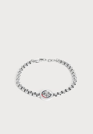 Bracelet chaîne en argent avec un pendentif boussole rond avec un motif étoile et un accent rouge sur fond blanc.
