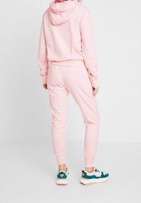 Rosa sweatshirt med huva, matchande rosa joggers och flerfärgade sneakers. Mjuk tyg, elastiska mudd och midja.