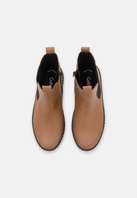 Tan leather ankle boots with a smooth finish, elastic side panels, and black rubber soles. Features two pull tabs for easy wear.