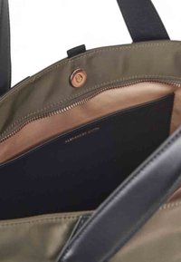 Borsa verde oliva con chiusura a zip e interno nero. Presenta un bottone a scatto in rame e manici in pelle nera. Tasca interna visibile.
