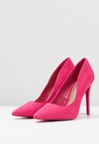 Escarpins en suede rose avec un bout pointu et un talon aiguille. Texture lisse, design épuré et style minimaliste.