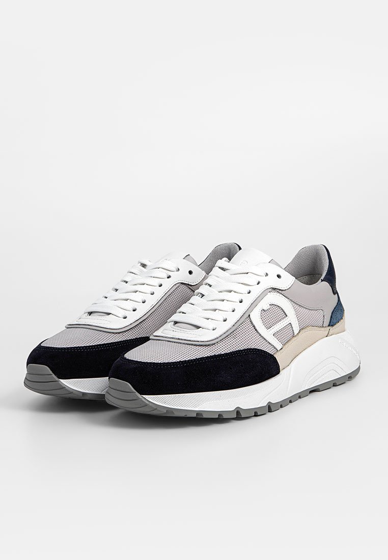 Graue und marineblaue Sneaker mit einem Obermaterial aus Mesh und Wildleder, das ein markantes Logo, weiße Schnürsenkel und eine dicke Gummisohle aufweist.