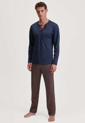 Haut de pyjama à manches longues navy avec un col à boutons et une poche, associé à un pantalon à motifs en bleu foncé et rouge à design géométrique.