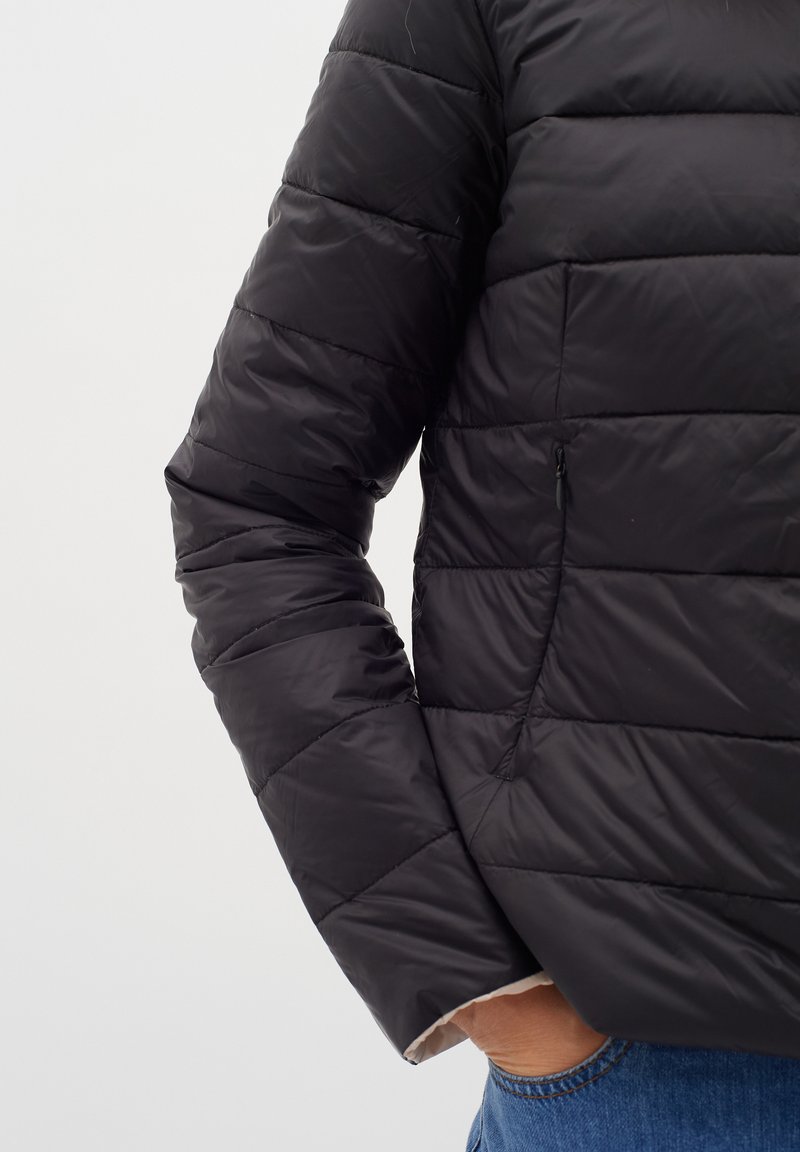Schwarze Pufferjacke mit gestepptem Muster, Reißverschluss-Seitentasche und kontrastierendem Bündchen. Das Material wirkt glänzend und leicht.