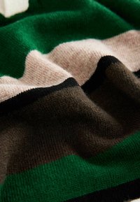 Kootud kampsun, millel on horisontaalsed triibud rohelises, helesinises, pruunis ja mustas värvitoonis. Pehme tekstuur ja hubane välimus.