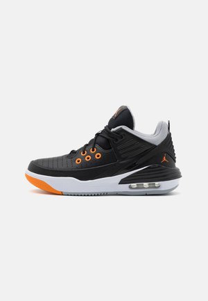 Zapatilla deportiva de media altura en negro y gris con ojales y logo naranjas, entresuela blanca con amortiguación visible de aire y punta de suela de goma naranja.