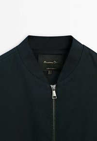 Veste bomber noire avec fermeture éclair argentée et col côtelé, étiquetée Massimo Dutti, taille medium, fabriquée au Maroc.