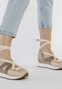 Sandales compensées beiges et grises avec des brides entrecroisées, en textile et en daim, avec une semelle intermédiaire blanche et des accents roses.