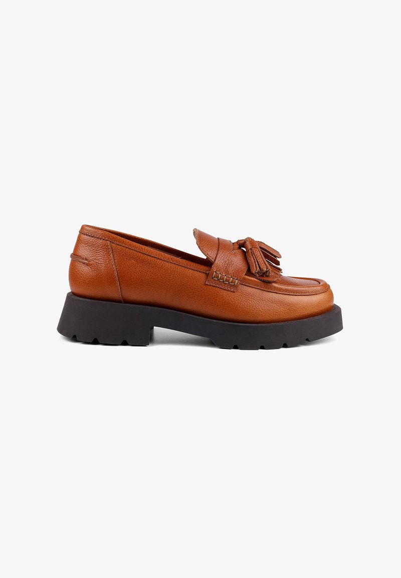 Brown leather slip-on shoe with a rounded toe, decorative fringed tassels, and a thick black rubber sole with tread.