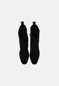 Czarne botki za kostkę wykonane z zamszu, charakteryzujące się eleganckim fasonem, spiczastym noskiem, pętlami do zakładania i bocznymi zamkami błyskawicznymi dla łatwego zakładania.