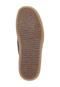 Gummisohle mit strukturiertem, gerilltem Oberflächen in hellbraun. Der Rand der Sohle ist abgerundet und geht in ein grünes Obermaterial über.