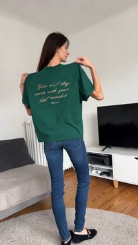 Camiseta verde de gran tamaño hecha de algodón, con un texto dorado en la espalda que dice: "Tu mejor día comienza con tu mejor mentalidad."
