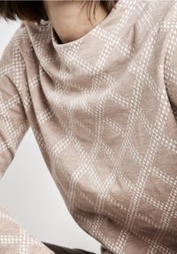 Maglione beige con motivo a diamante diagonale e testurizzato in bianco. Tessuto morbido con collo alto e maniche aderenti.