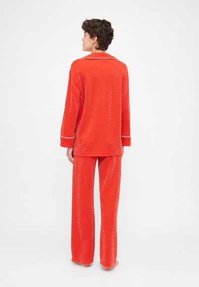 Red, sparkly pajama set featuring a long-sleeve top with a collar and matching wide-leg pants, designed for comfort and relaxation.