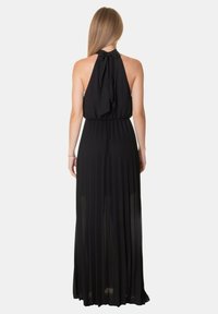Abito maxi plissè nero con collo all'americana e fiocco annodato. Tessuto morbido con una sezione inferiore trasparente, che mette in risalto un drappeggio elegante.