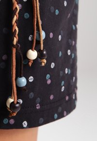 Zwarte stoffen shorts met meerkleurige stippen en drie gevlochten koorden versierd met houten kralen in blauw, wit en bruin.