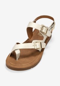 Beige Leder-Sandalen mit zwei verstellbaren Riemen, goldenen Beschlägen und einer braunen strukturierten Innensohle. Verfügt über eine flache Sohle und ein minimalistisches Design.
