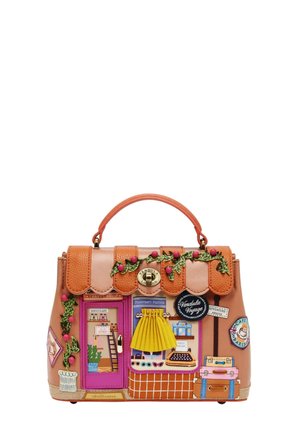 Tan handtas met kleurrijk ontwerp van een reiswinkelgevel, met een roze deur, gele rok-gordijn, koffers en decoratieve groene wijnstokken met rode bessen.