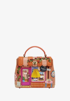 Tan handtas met kleurrijk ontwerp van een reiswinkelgevel, met een roze deur, gele rok-gordijn, koffers en decoratieve groene wijnstokken met rode bessen.