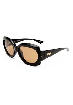 Μαύρα υπερμεγέθη γυαλιά ηλίου με παχιά πλαίσια και φακούς καφέ απόχρωσης, με χρυσή λεπτομέρεια στο τμήμα του βραχίονα ναού.