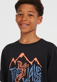Zwarte katoenen t-shirt met een grafisch ontwerp van oranje bergen en blauwe tekst "Frozen Wave Cult" op de voorkant. Korte mouwen.