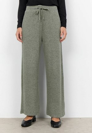Pantalon large gris-vert avec taille à cordon de serrage, fabriqué dans un tissu doux et texturé. Associé à des chaussures plates noires.