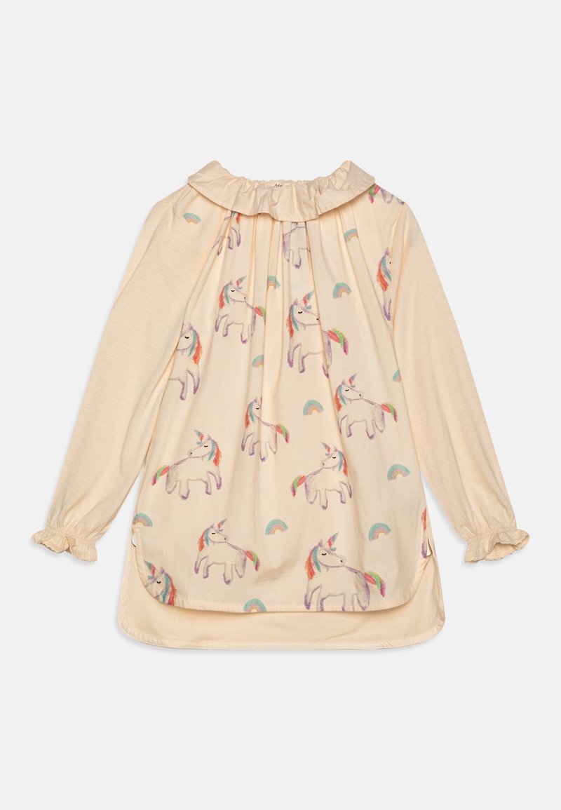 Chemise à manches longues de couleur crème avec col et poignets volantés, ornée de broderies de licornes et d'arcs-en-ciel sur toute la partie avant.