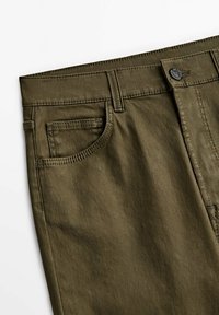 Olivegrüne Baumwollhose mit glatter Textur, ausgestattet mit einer Fronttasche, Gürtelschlaufen und einem Metallknopfverschluss.