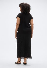 Black short-sleeve top with rounded hem paired with a long black skirt featuring scattered sparkles and a scalloped lace trim at the bottom.