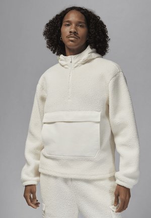 Hvid fleece sweater med halv-zip krave, forlommer og tekstureret stof. Designet har en afslappet pasform og minimale detaljer.