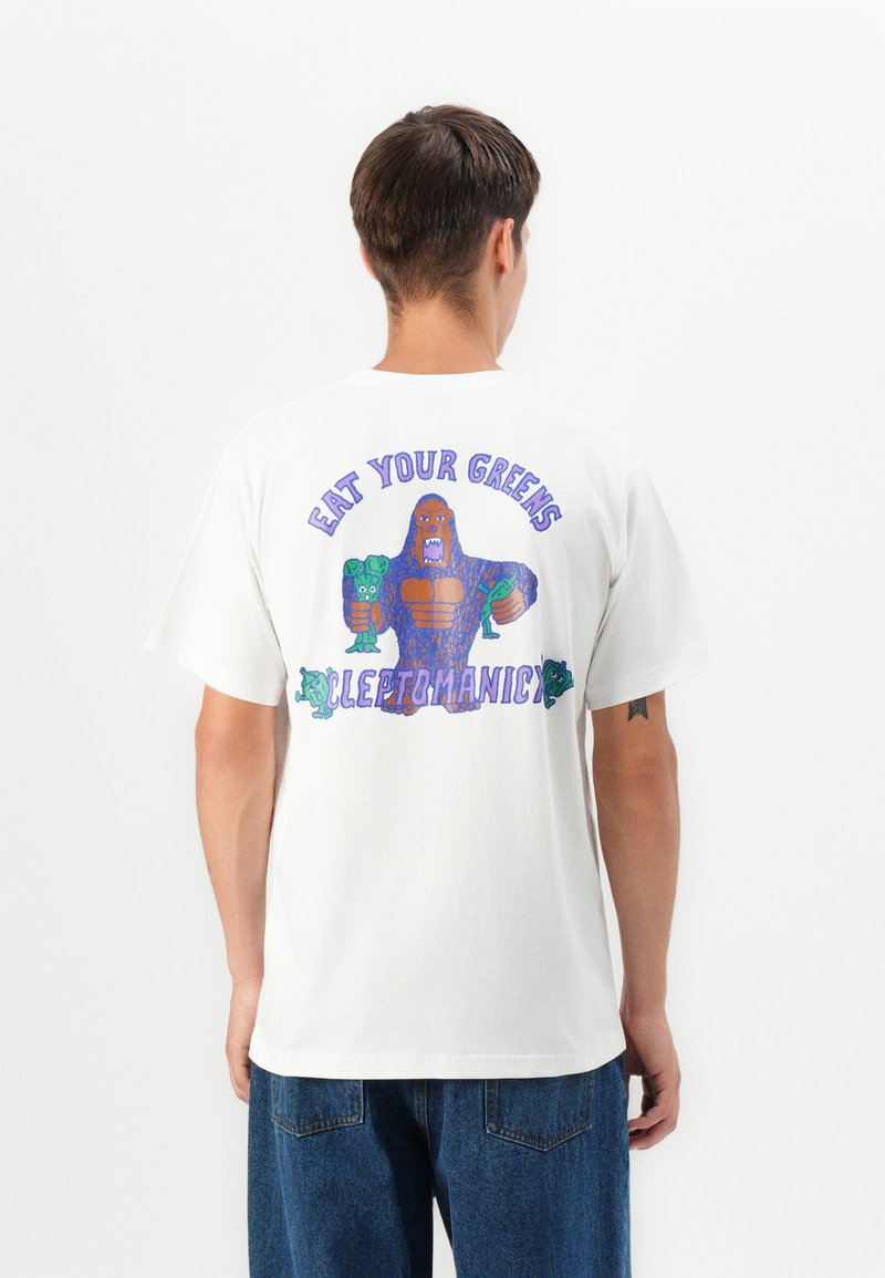 Weißes Baumwoll-T-Shirt mit einem bunten Grafikdesign eines Cartoon-Figuren, der Gemüse hält, und dem Text "ESS DEIN GRÜNZEUG" darüber.