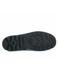 Suela de zapato de goma negra con un patrón de tread profundo y texturas variadas, incluyendo secciones en zigzag y en capas para mayor tracción.