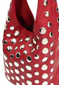 Rote Ledertasche mit zahlreichen glänzenden runden silbernen Nieten, die ihre Oberfläche bedecken.
