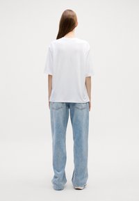 Witte korte mouwen t-shirt in combinatie met lichtblauwe oversized denim jeans. Eenvoudige, relaxed fit met een zachte textuur en geen zichtbare patronen.