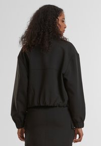 Mustar pruunistatud lõikega sweatshirtyl on ümar kaelus, elastne allosa ja kergelt langenud õlavarre õmblused, valmistatud tekstuurilisest kangast.
