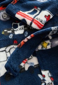 Coperta di pile blu navy con motivi colorati di veicoli, inclusi ambulanze e auto della polizia, con superficie morbida e strutturata per il calore.